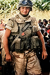 UN PARACADUTISTA ITALIANO DELLA 10ª COMPAGNIA “DRAGHI” IN MIMETICA DESERTICA POSA SORRIDENTE TRA LA POPOLAZIONE LOCALE SOMALA DURANTE LA MISSIONE IBIS.